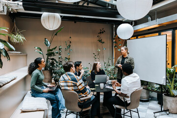 Female entrepreneur conducting business meeting with team at office