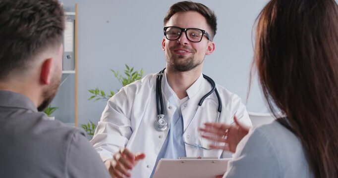 Doctor specializing in pregnancy planning gives a high five to a couple during consultation at the hospital. The couple is seeking healthcare, medical advice and checkup for pregnancy planning.