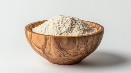 A bowl made of wood filled with wheat flour, set against a plain white backdrop.