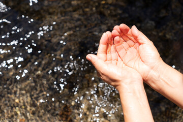 Close up of hands with water collected from a beautiful crystal-clear high mountain stream on a day of sports to cool off