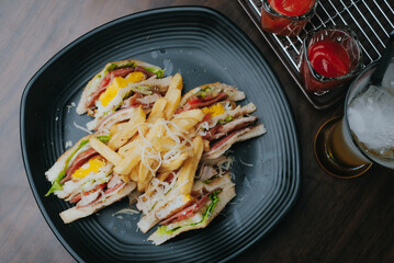 Club sandwich and fries isolated on black plat and wooden table background. Top View and side view