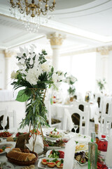 The festive table in the restaurant is decorated with a beautiful bouquet of white flowers.