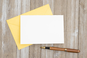 Blank greeting card with a envelop with pen on wood