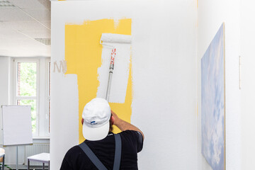 painter painting a yellow wall with white color