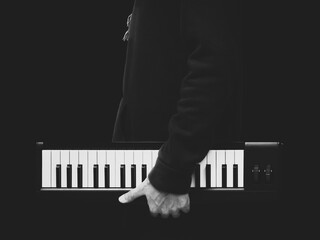 BW male musician holding music keyboard, isolated on black. music background