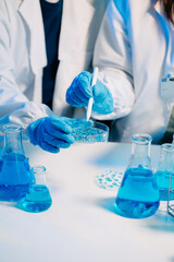 scientists in lab coats conducting research, handling glassware, and working with chemicals