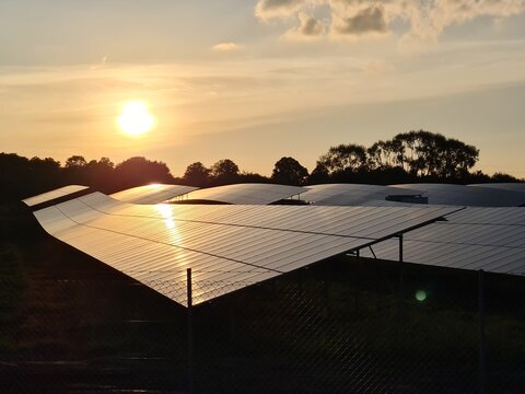 Dark silhouette of a solar park for power generation with the light of the sunset reflected in the solar modules.