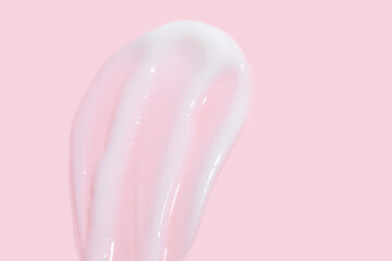 Smear of cosmetic cream or lotion on pink background. smear smudge stroke on color background. Creamy beauty product closeup