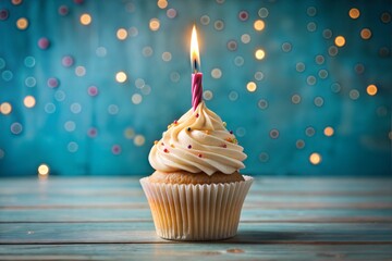Single cupcake with candle against bokeh background on wooden surface