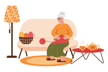 Cute old lady in yellow sweater doing needlework sitting on sofa near floor lamp