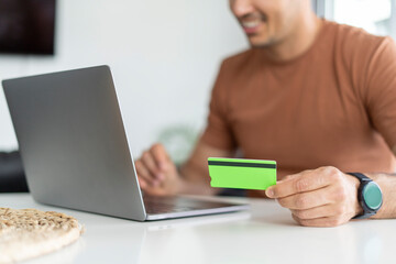 Man entering payment information with credit card and laptop.