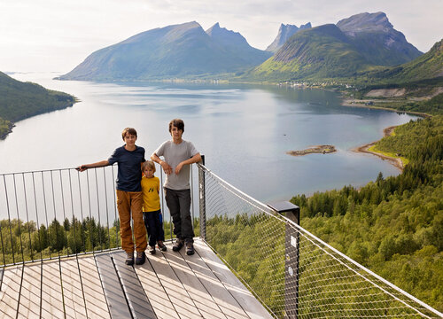 Children, standing on the edge of a 44 meter long viewing platform, overlooking the water of Bergsfjord, enjoying the view on Senja island, Norway