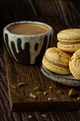 Light brown, beige french macaroons  on the dark background with cup of coffee