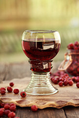 Medicinal wine made of fresh hawthorn berries in a cup made of so called forest glass full of air bubbles