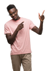 Fototapeta premium Young african american man wearing pink t-shirt smiling and looking at the camera pointing with two hands and fingers to the side.