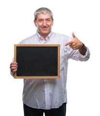 Handsome senior teacher man holding blackboard over isolated background very happy pointing with hand and finger