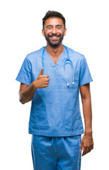 Adult hispanic doctor or surgeon man over isolated background doing happy thumbs up gesture with...
