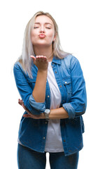 Young blonde woman over isolated background looking at the camera blowing a kiss with hand on air...