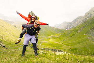 Sporty caucasian couple hikers having fun hiking outdoors do piggyback enjoy holidays - Happy healthy friends laughing together do sports - People outdoors concept