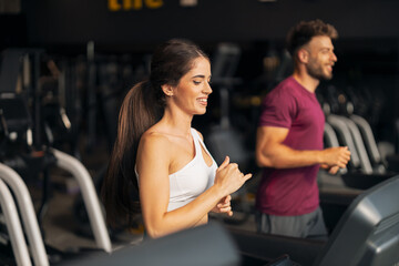 Fototapeta premium A beautiful athletic young adult woman using a treadmill at the gym
