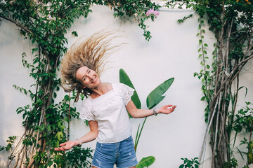 Young woman with flowing hair enjoying a sunny day in a lush garden with green plants