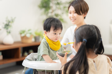 0歳の弟に離乳食を与える姉