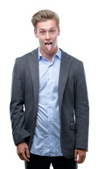 Young handsome blond business man sticking tongue out happy with funny expression. Emotion concept.