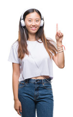 Young asian woman listening to music wearing headphones isolated background surprised with an idea or question pointing finger with happy face, number one