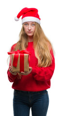 Blonde teenager woman wearing santa claus hat with a confident expression on smart face thinking serious