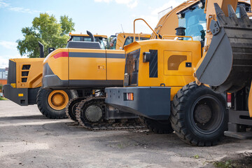 Yellow construction equipment stands in a row.