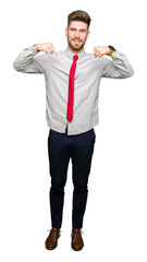 Young handsome business man looking confident with smile on face, pointing oneself with fingers proud and happy.