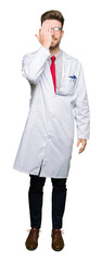 Fototapeta premium Young handsome scientist man wearing glasses covering one eye with hand with confident smile on face and surprise emotion.