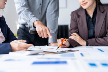 Business team analyzing financial documents and pointing at charts