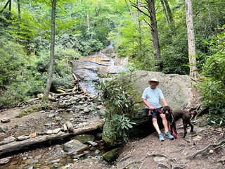 A man and his standard poodle near a waterfall in the Pisgah National Forest near burnsville, NC USA