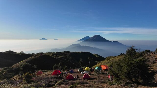 4k video footage of Hikers are camping at Mount Prau peak in Dieng, Wonosobo, Indonesia with mount sindoro sumbing and clear blue sky background.