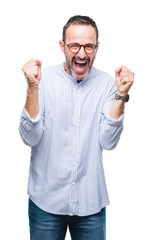 Naklejka premium Middle age hoary senior man wearing glasses over isolated background celebrating surprised and amazed for success with arms raised and open eyes. Winner concept.