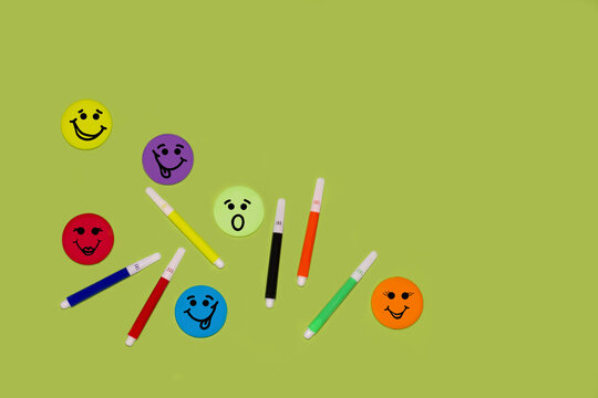 Colorful emoticons arranged in a circle with markers on a bright green background. Creativity, fun, positive, back to school, play, collaborative education, icon set,smiles