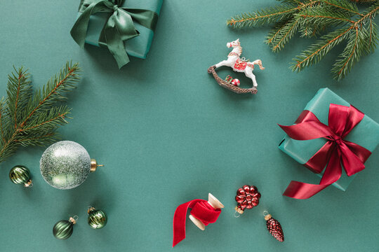 Overhead view of wrapped Christmas gifts, fir branches, Christmas baubles, ornaments and decorations on a green background