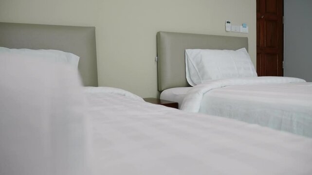 Two white beds with white sheets and pillows. One bed has a towel on it. The beds are in a hotel room