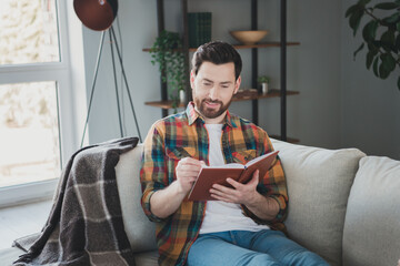 Photo of nice young man sit couch write diary wear stylish checkered shirt modern light cozy...