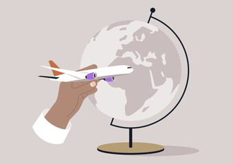 A hand, wearing a white sleeve, holds a white toy airplane with purple engines, prepared to launch it into the air around the globe