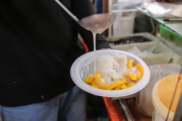  A chef is preparing sticky rice with milk, seen close up