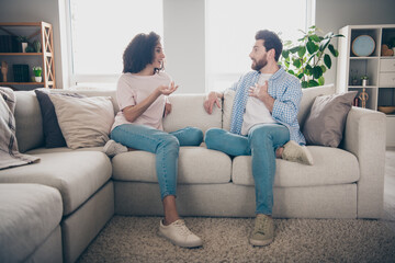 Obraz premium photo of positive girl guy sit divan couch speak talk in apartment flat indoors