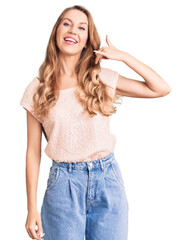 Fototapeta premium Young beautiful caucasian woman with blond hair wearing casual clothes smiling doing phone gesture with hand and fingers like talking on the telephone. communicating concepts.