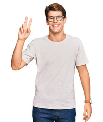 Handsome caucasian man wearing casual clothes and glasses smiling looking to the camera showing fingers doing victory sign. number two.