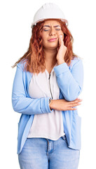 Young latin woman wearing architect hardhat touching mouth with hand with painful expression because of toothache or dental illness on teeth. dentist
