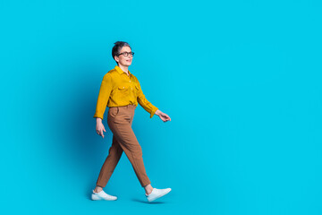 Full length photo of confident attractive lady dressed shirt glasses walking emtpy space isolated blue color background