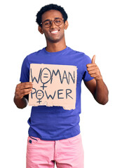 African handsome man holding woman power banner smiling happy and positive, thumb up doing excellent and approval sign