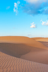 ndless desert dunes with undulating orange sand, forming stunning natural patterns in the sun