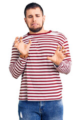 Young handsome man wearing striped sweater disgusted expression, displeased and fearful doing disgust face because aversion reaction.